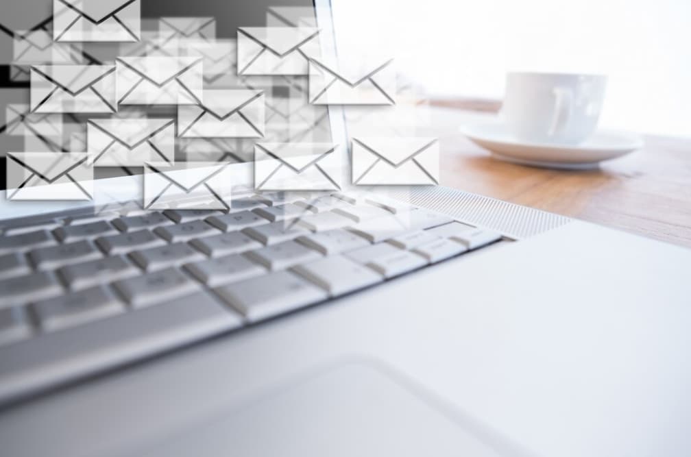 Envelopes flying out of a laptop screen, suggesting digital email