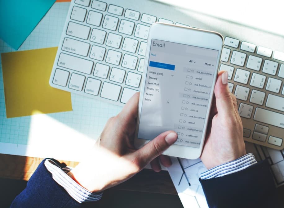 Close-up of a hand holding a smartphone with an open email inbox