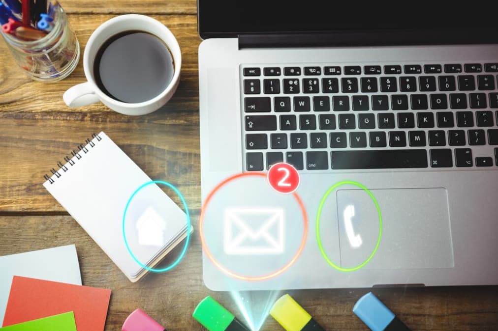 A workspace with a laptop displaying email notifications, coffee, and stationery