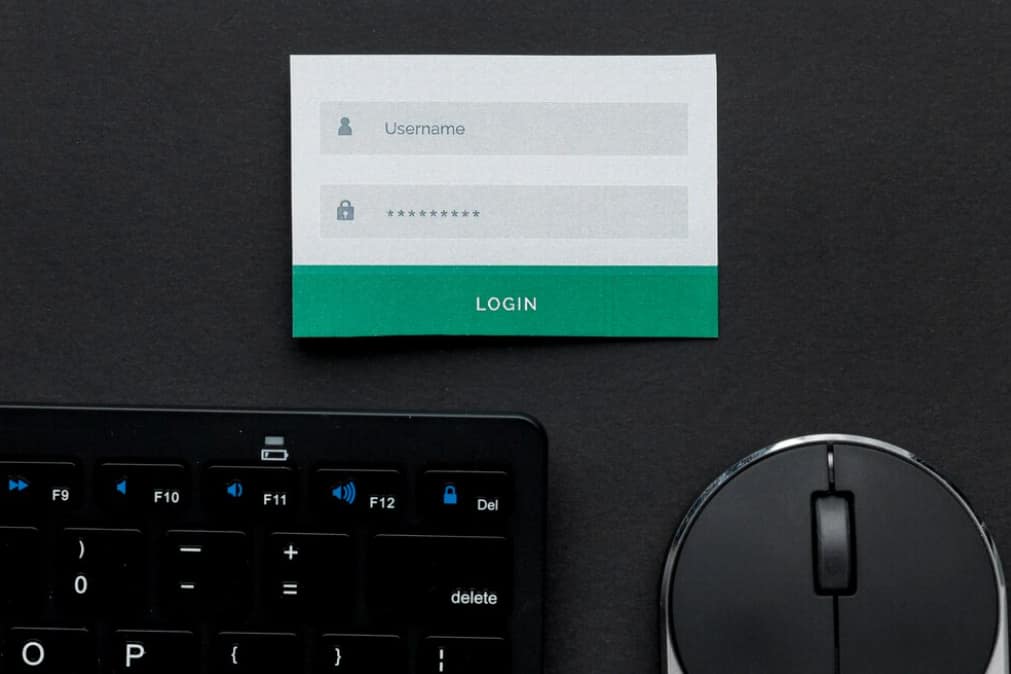 Login paper on a keyboard, next to a mouse on a dark surface