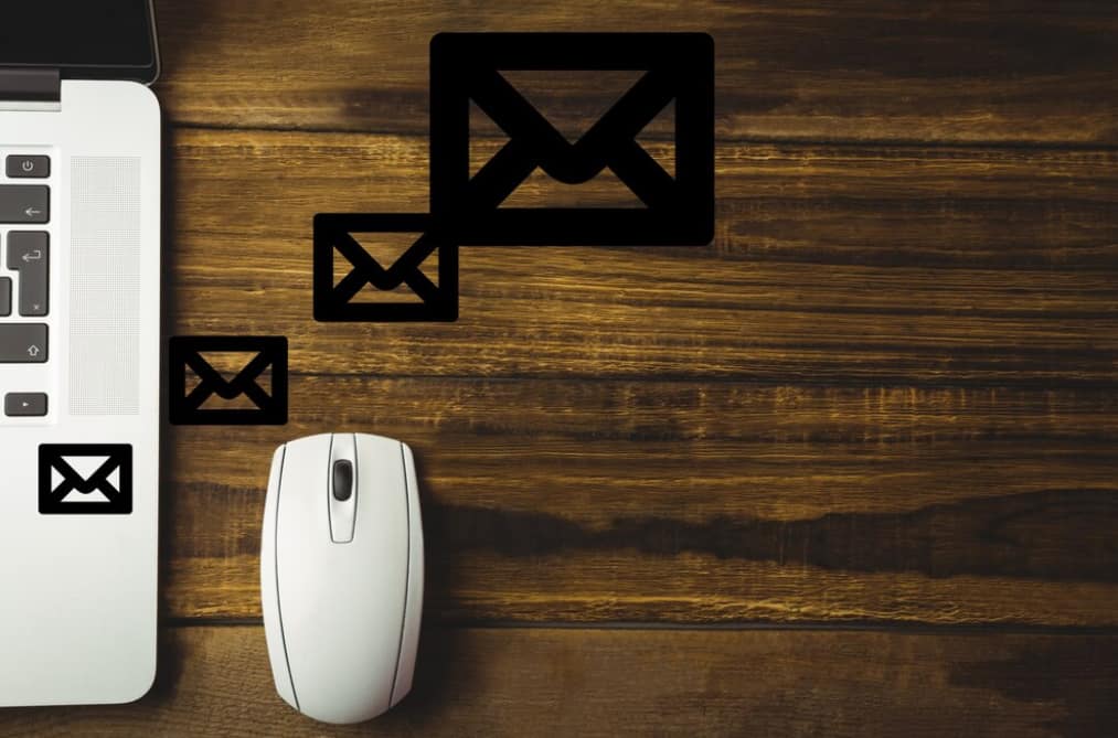 A laptop with email icons on a wooden table